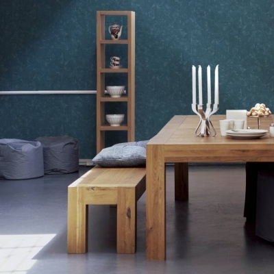 Sala de jantar com mesa e banco de madeira clara, castiçal com velas brancas e estante com louça