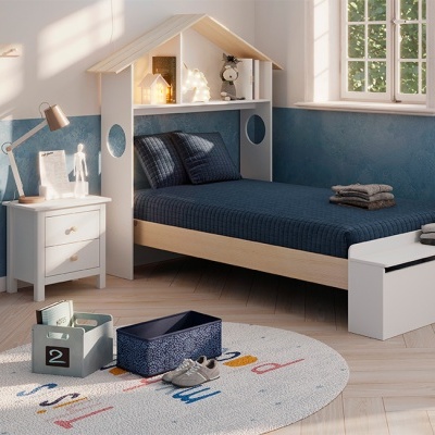 Quarto infantil com cama em madeira clara e cabeceira em forma de casa, roupa de cama azul, mesa de cabeceira branca, tapete redondo e parede azul 