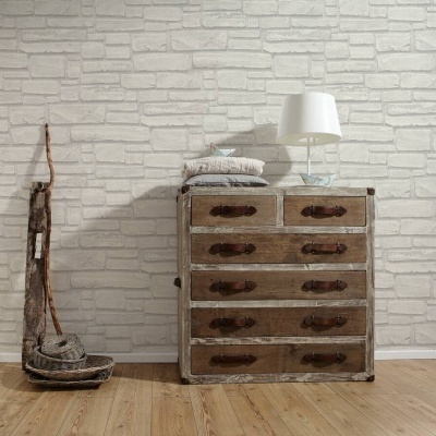 Cómoda rústica de madeira com cinco gavetas e puxadores de couro, decorada com almofadas e lâmpada branca, parede de tijolos brancos e piso de madeira clara