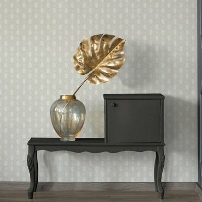 Consola preta com vaso de vidro e folha dourada e caixa preta contra parede com padrão claro