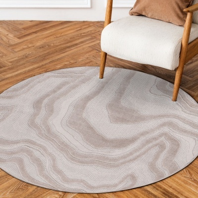 Tapete redondo cinza com padrão ondulado e cadeira de madeira com assento branco