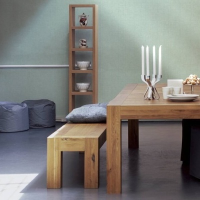 Mesa de madeira com bancos e velas, almofada e estante ao fundo