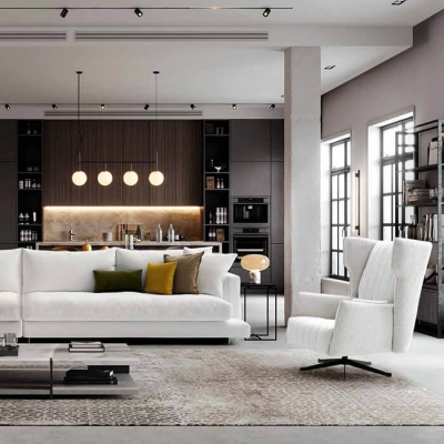 Sala de estar moderna com sofá branco, poltrona branca, almofadas coloridas, mesa de centro preta e cozinha escura ao fundo