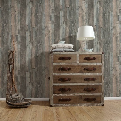 Móvel rústico com gavetas, lâmpada de mesa branca, almofadas, parede de madeira envelhecida e chão de madeira clara