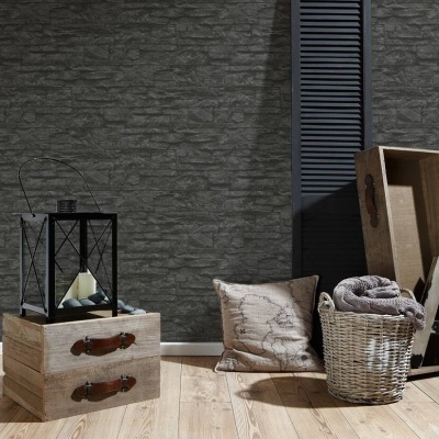 Sala com parede cinzenta textura pedra, cômoda de madeira clara, lanterna preta, almofada bege, cesto de vime com manta e cabide de madeira