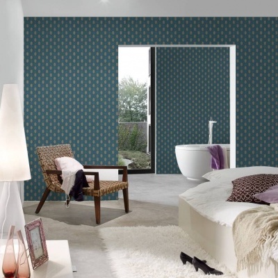 Quarto moderno com cadeira em madeira e almofadas, parede azul com padrão, cama branca com manta e almofadas e candeeiro alto.