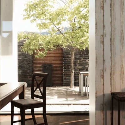 Área interior com mesa de madeira escura e cadeiras, parede com papel de riscas verticais