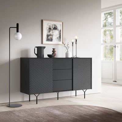 Aparador preto com textura geométrica e luminária de pé preta junto à parede cinza