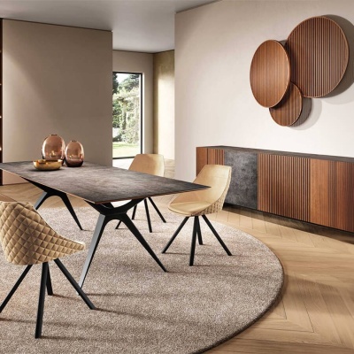 Sala de jantar com mesa retangular cinzenta, duas cadeiras bege acolchoadas, tapete circular cinzento claro, móvel lateral de madeira e painéis redondos de madeira na parede