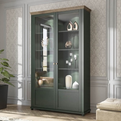 Vitrine verde escura com portas de vidro e objetos decorativos numa sala com parede clara