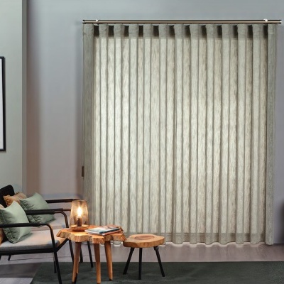 Cortina vertical bege claro transparente numa sala moderna com cadeirão e mesas de madeira.