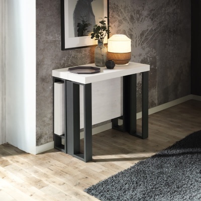 Mesa auxiliar branca com estrutura preta e objetos decorativos num ambiente moderno