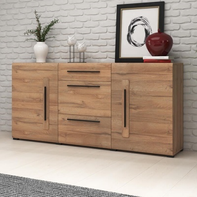 Aparador de madeira clara com gavetas e portas, decorado com vasos e quadro, contra parede de tijolos brancos