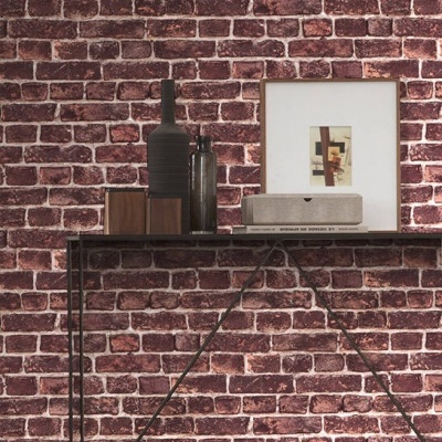 Mesa de consola com objetos decorativos e quadro frente a parede de tijolos vermelhos