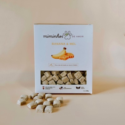 Embalagem de snacks para cães banana e mel com biscoitos quadrados à frente.