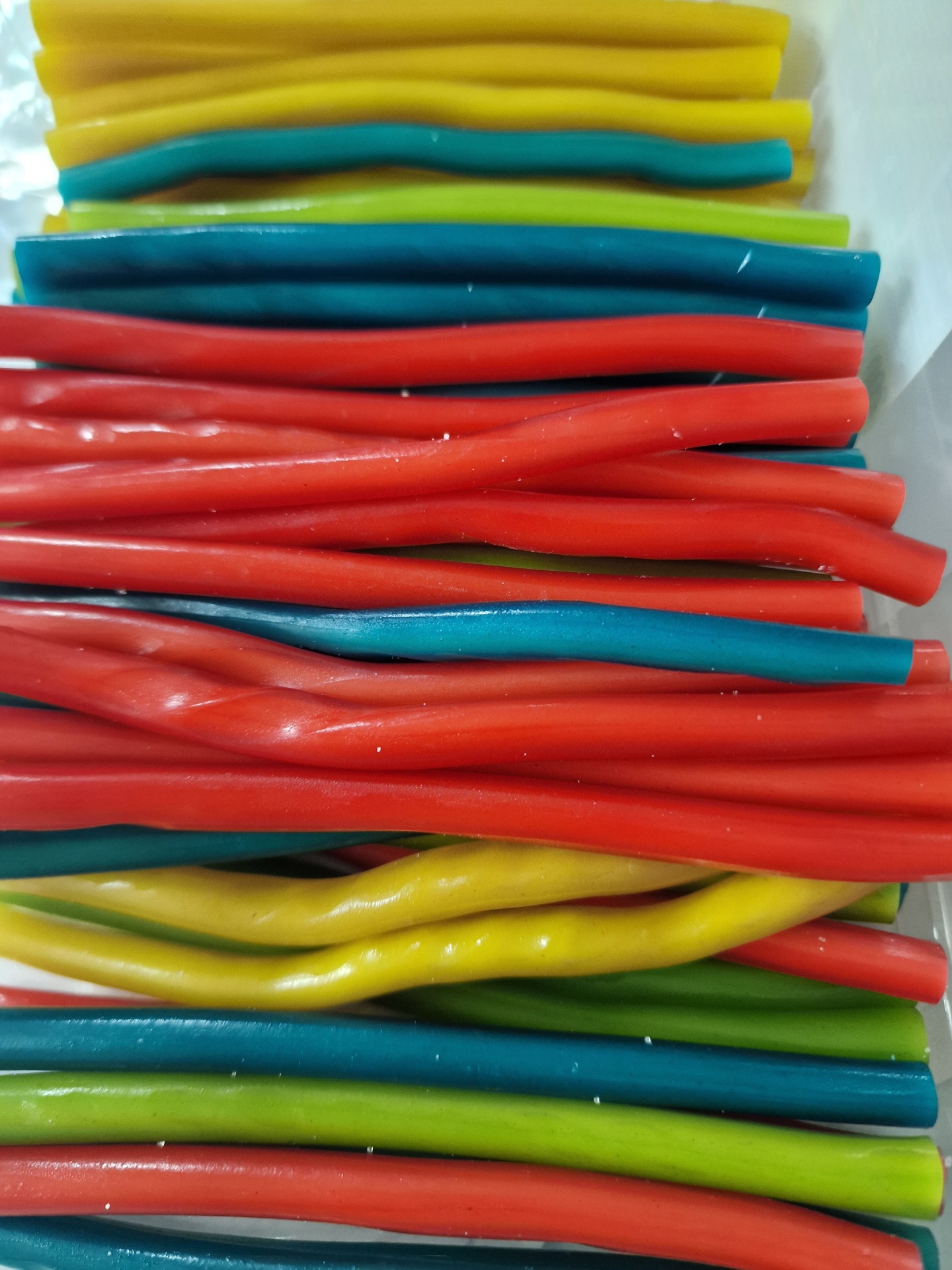 Cordões de goma coloridos em amarelo, azul, vermelho e verde sobre fundo branco