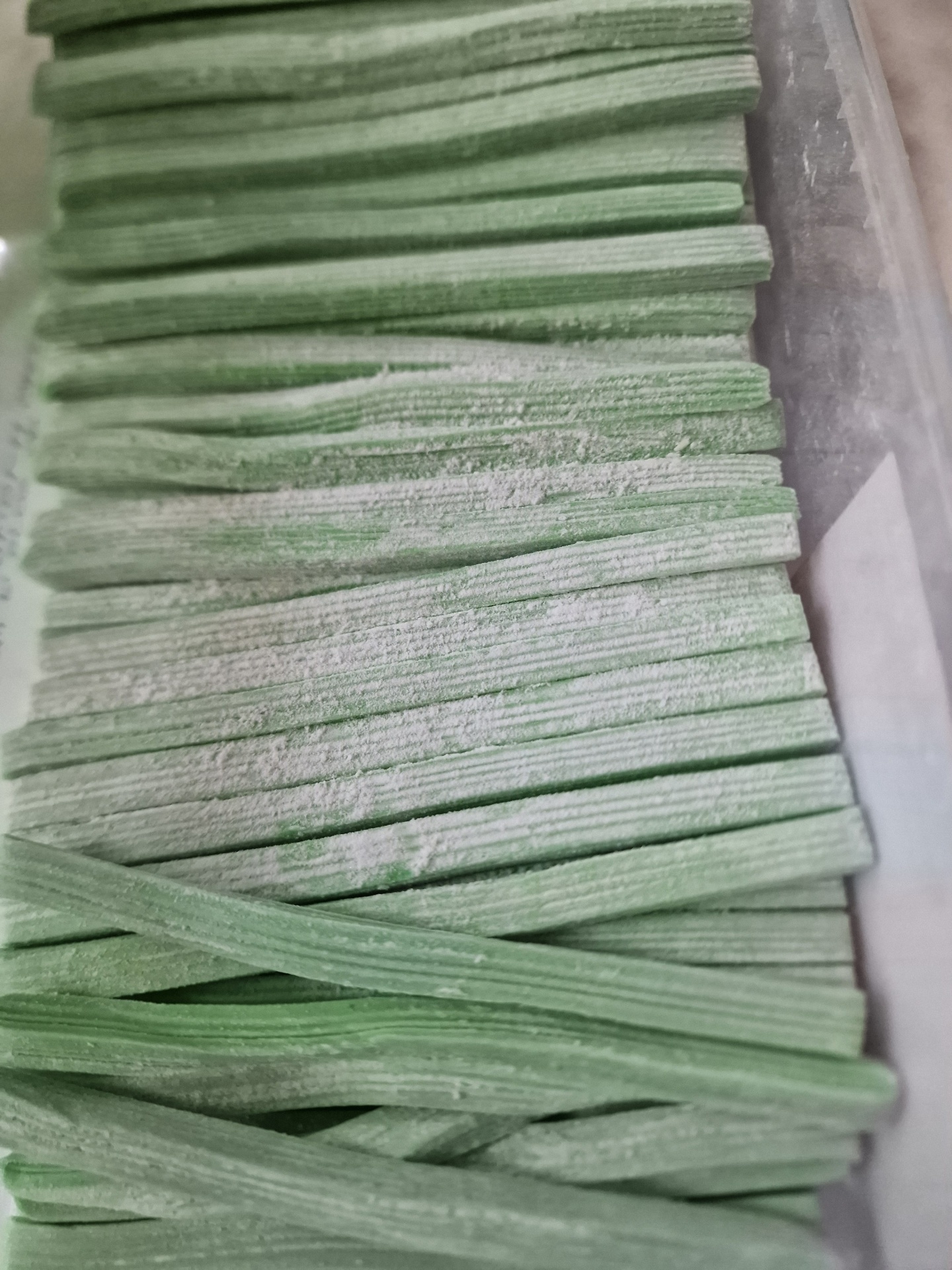 Palitos de pasta verde com pó branco dentro de recipiente transparente