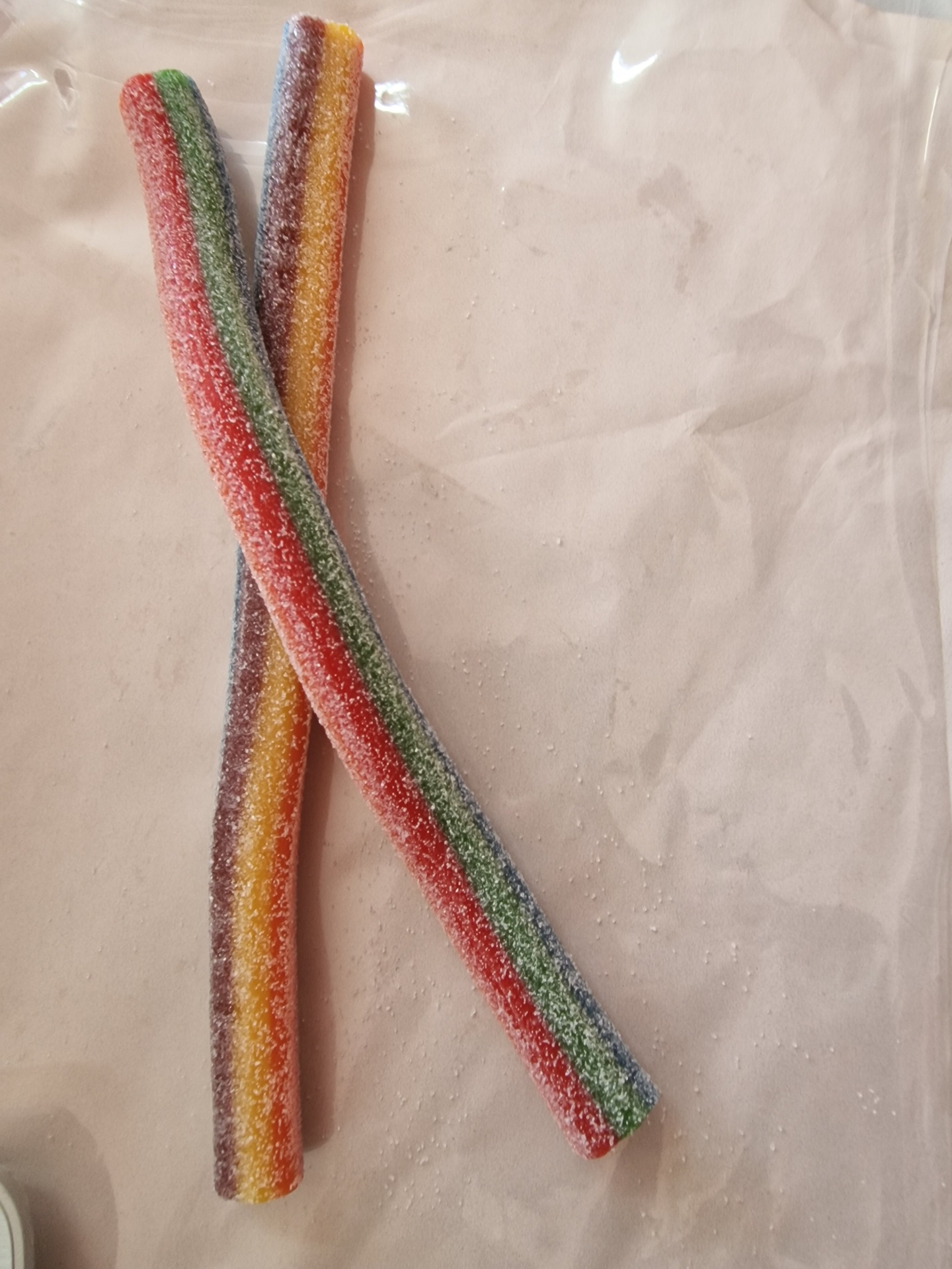 Dois bastões de doces coloridos com açúcar granulado sobre tecido claro