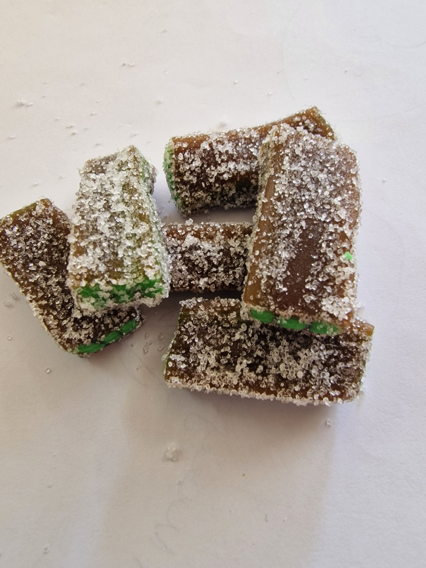 Pedaços de doce com açúcar cristal, verde e castanho, sobre fundo branco