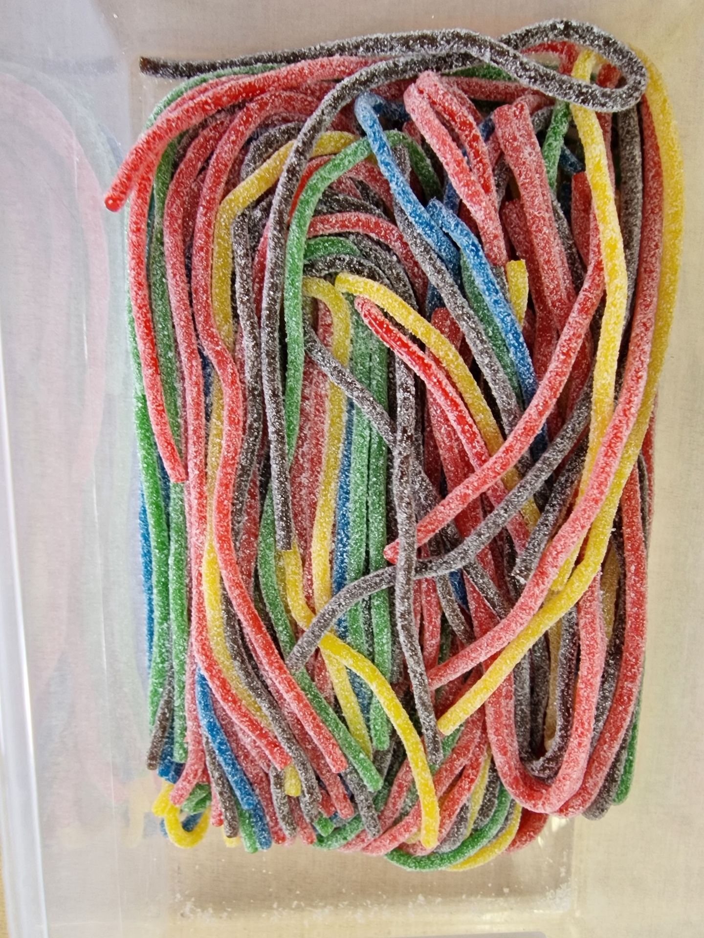 Doces em gelatina coloridos, compridos e açucarados em caixa de plástico