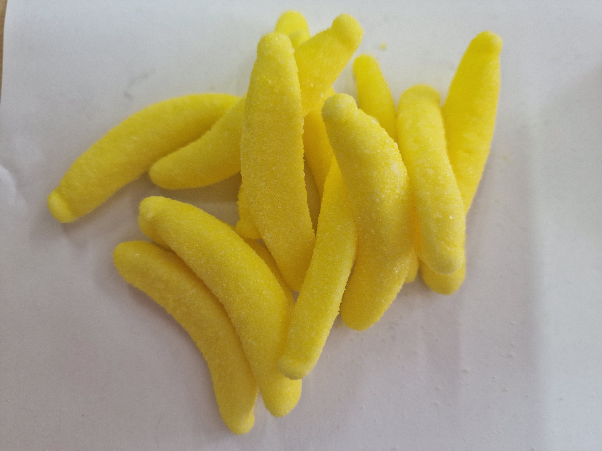 Doces amarelos em forma de banana sobre superfície branca