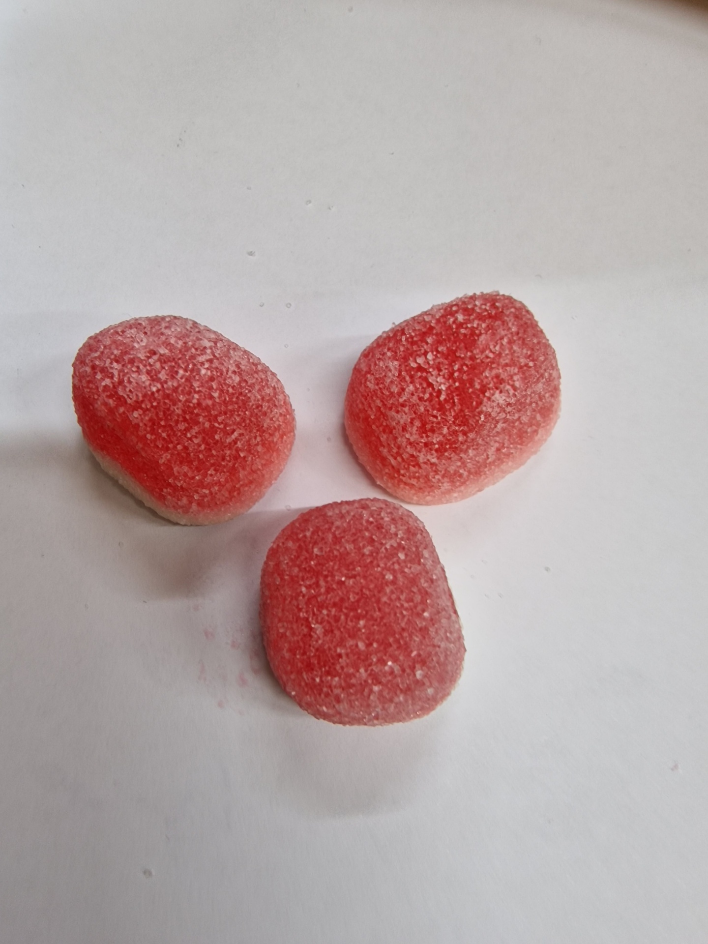 Três rebuçados vermelhos açucarados em fundo branco