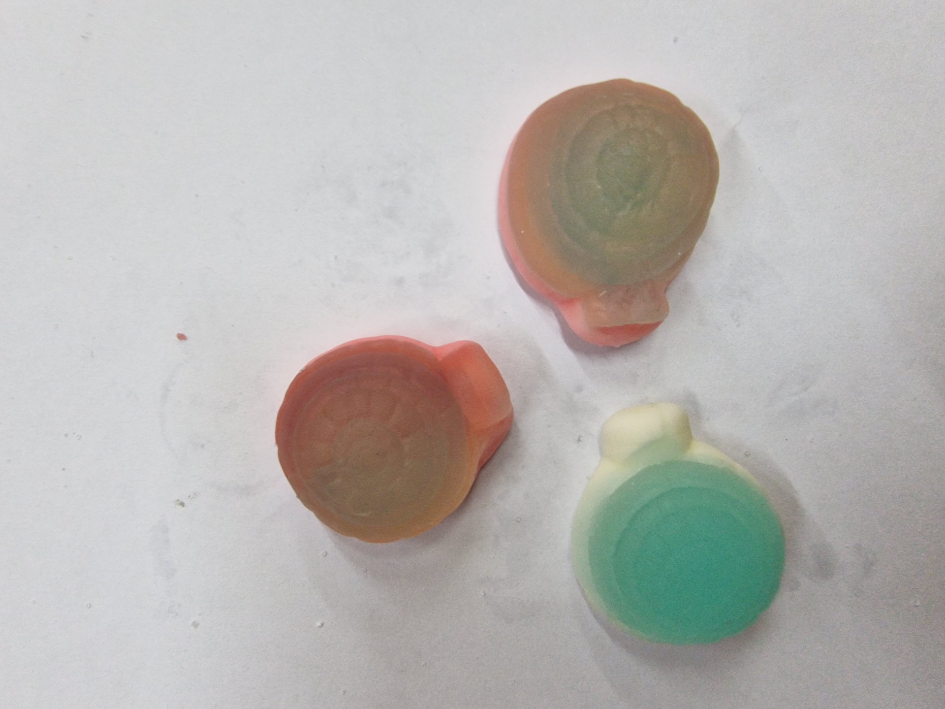 Três pequenos objetos arredondados coloridos sobre fundo branco