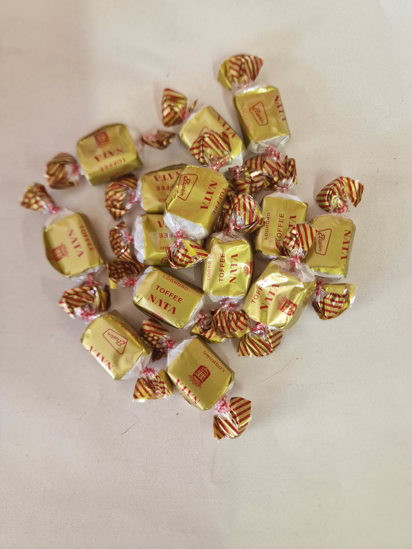 Doces Toffee embalados individualmente em papel dourado com fita listrada