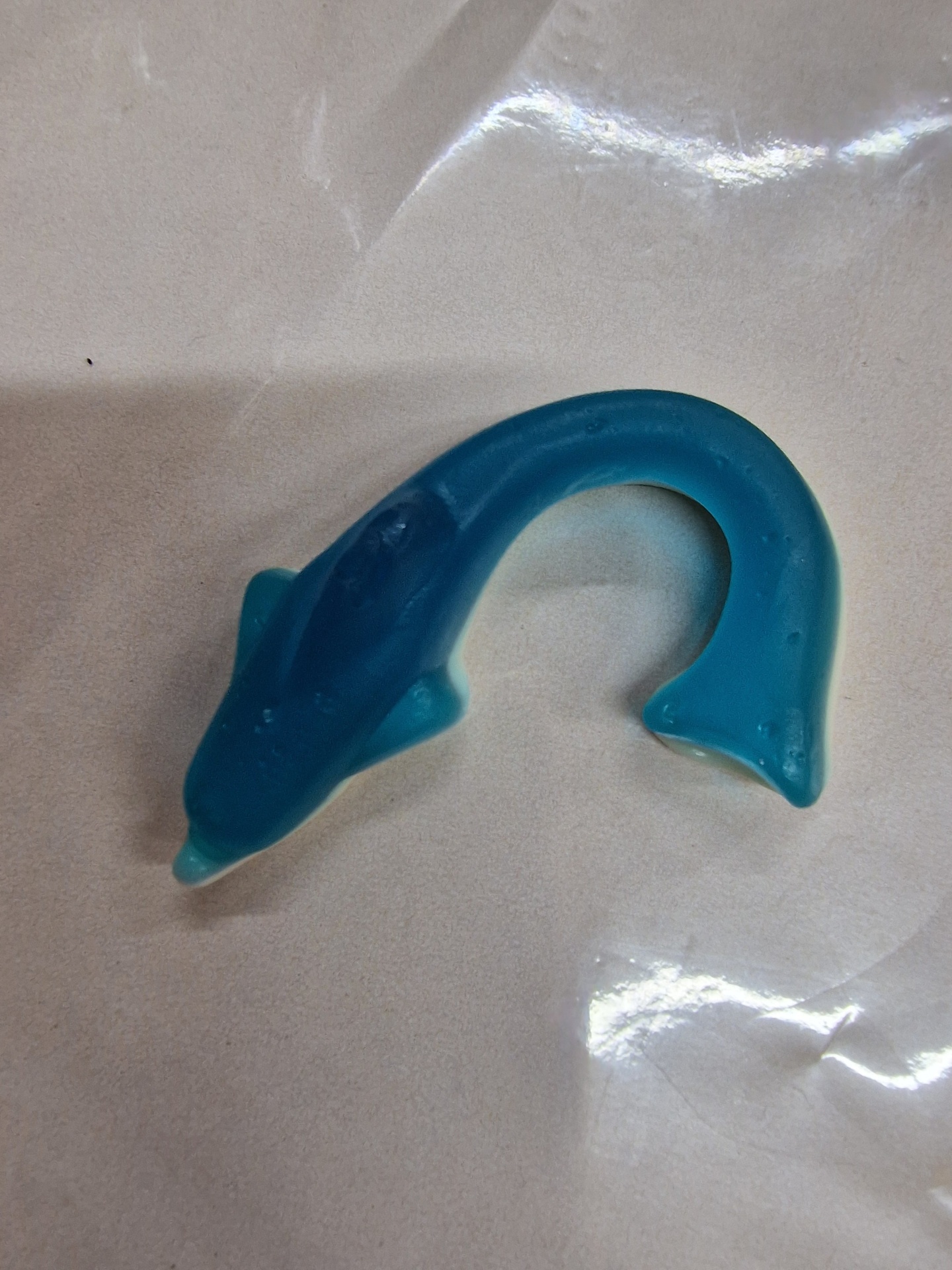 Brinquedo em forma de peixe azul sobre fundo branco com plástico transparente