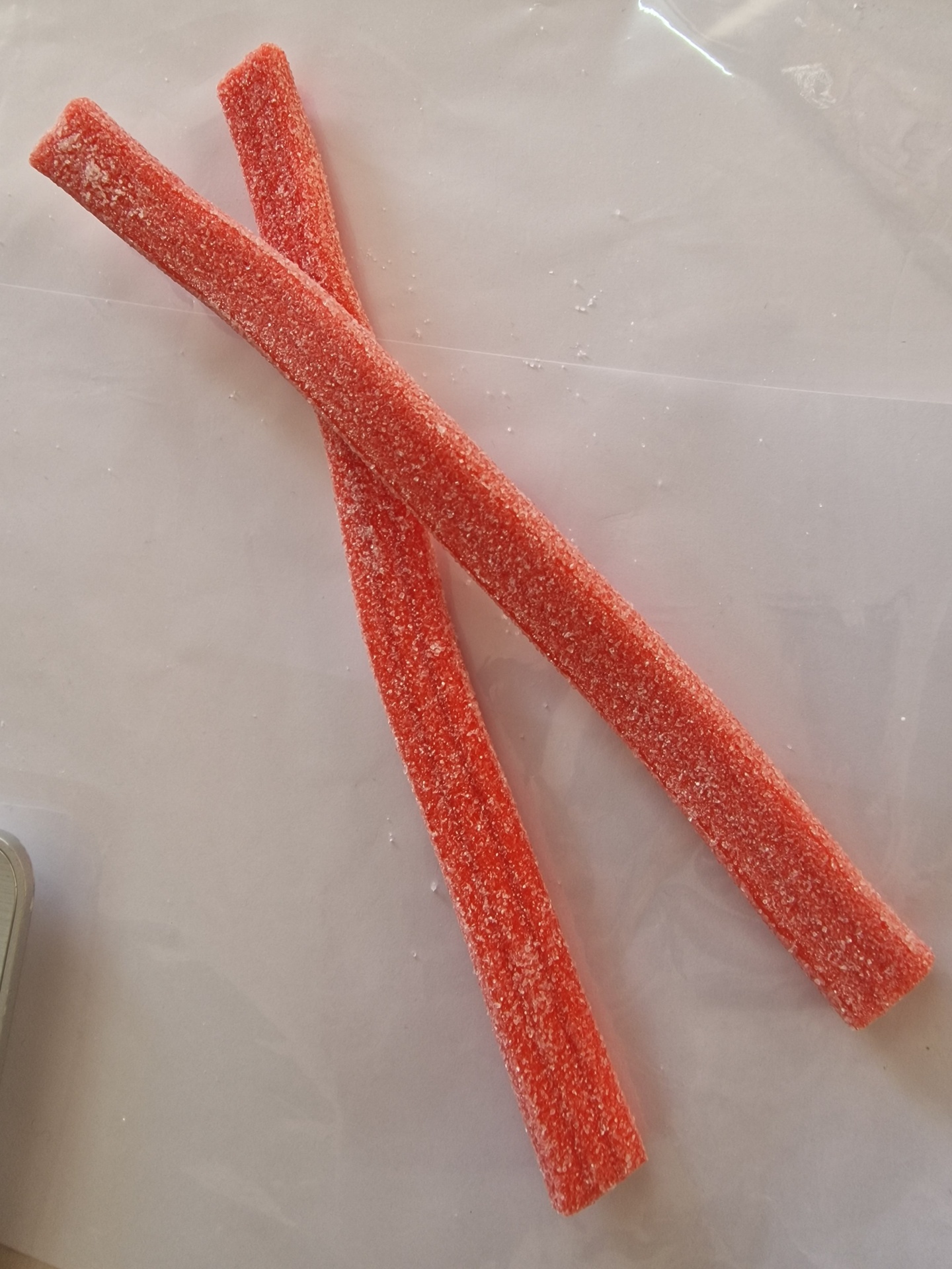 Dois tiras de doce vermelho com açúcar num fundo branco