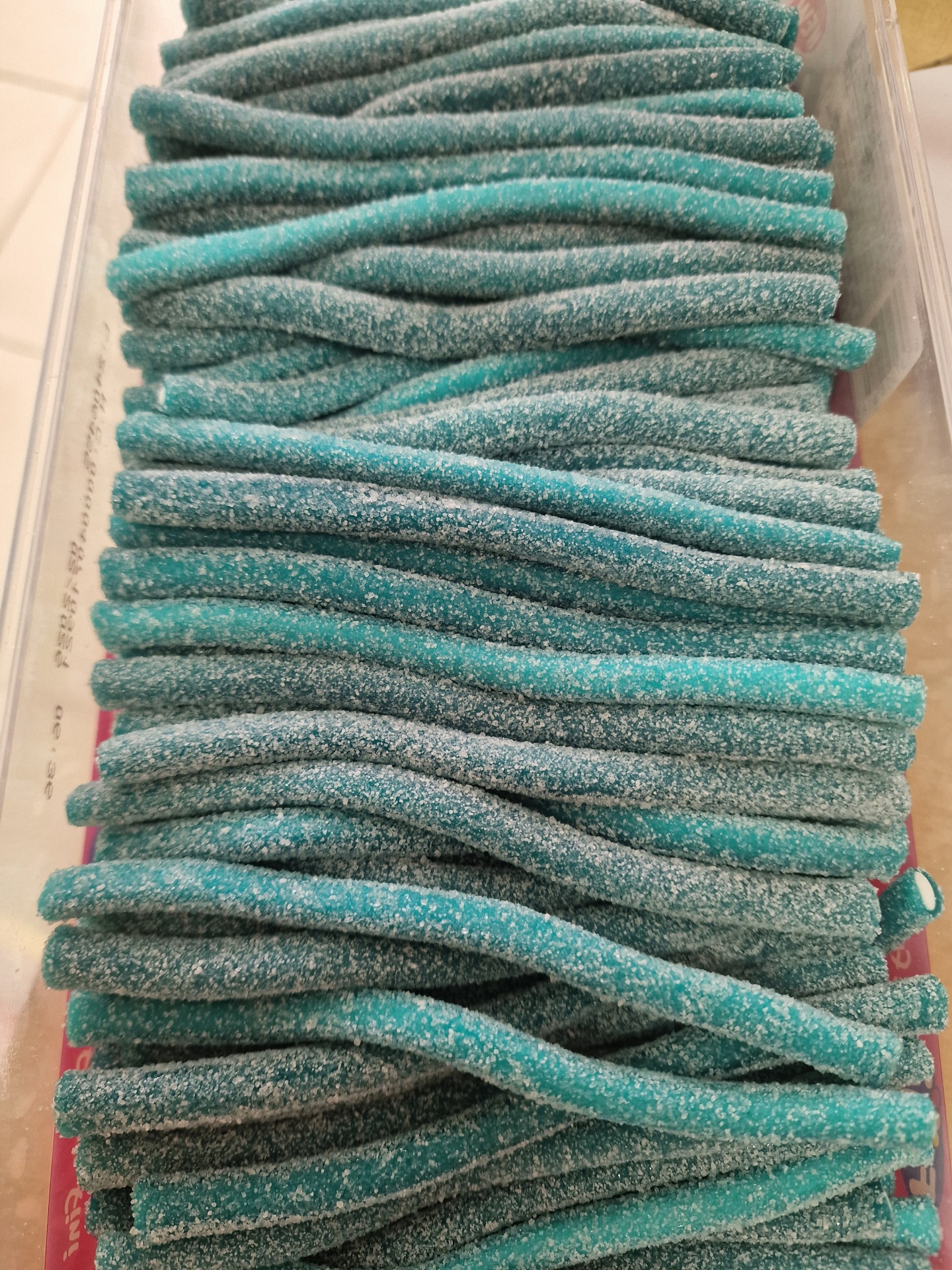 Bastões de doce azul com polvilho branco em caixa transparente