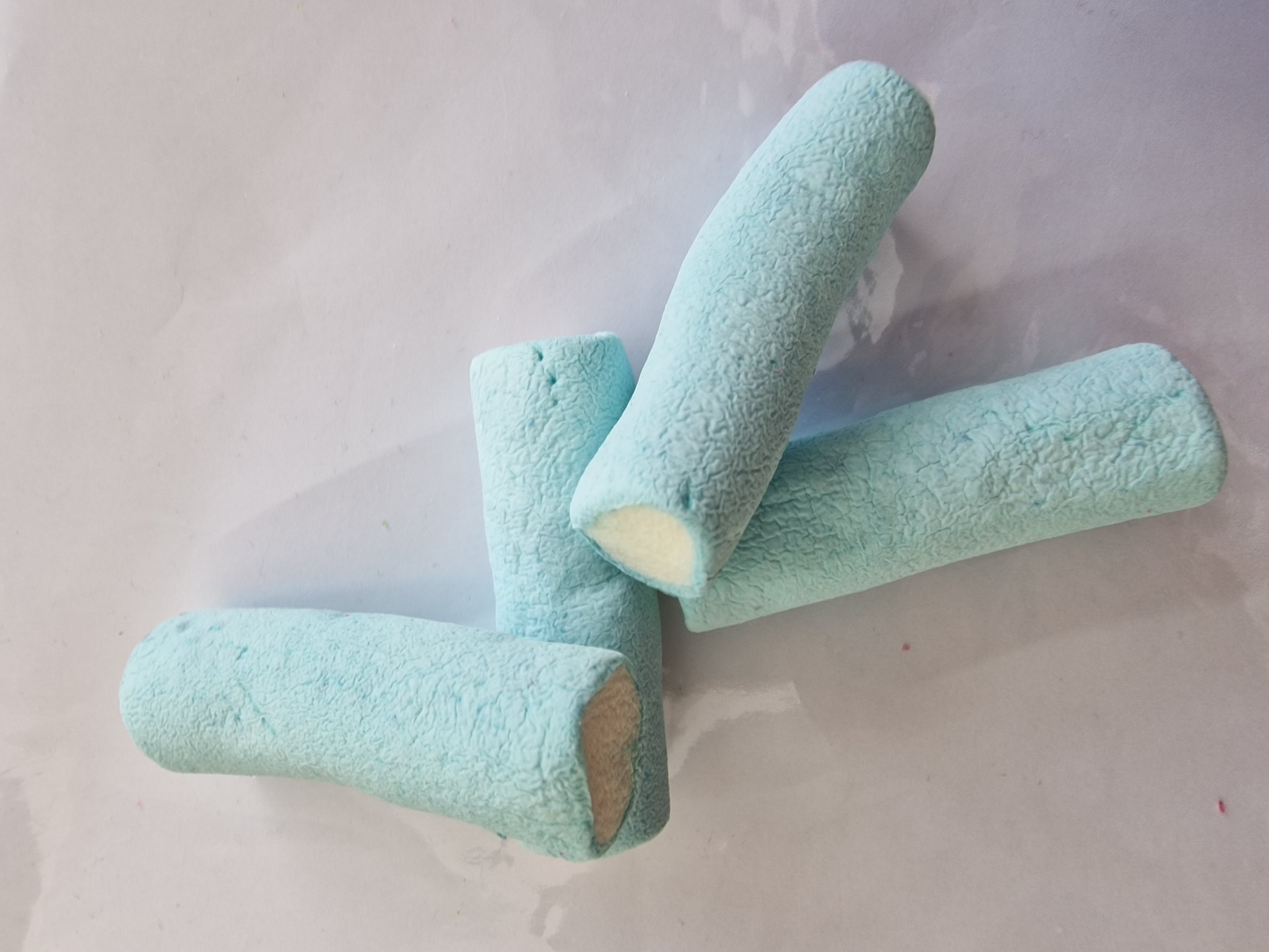 Marshmallows azuis claros com interior branco sobre superfície brilhante