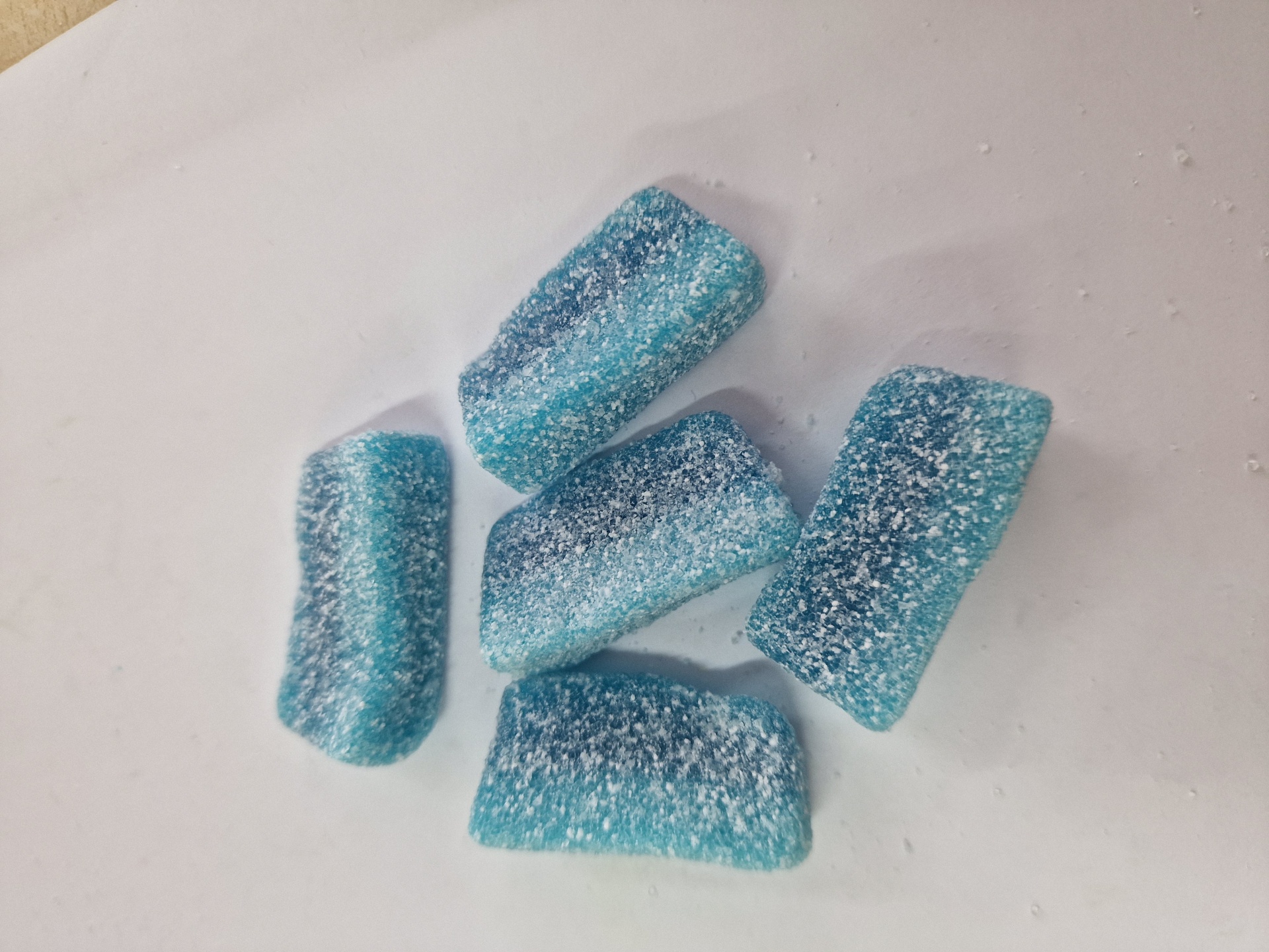 Gomas azuis com açúcar sobre superfície branca