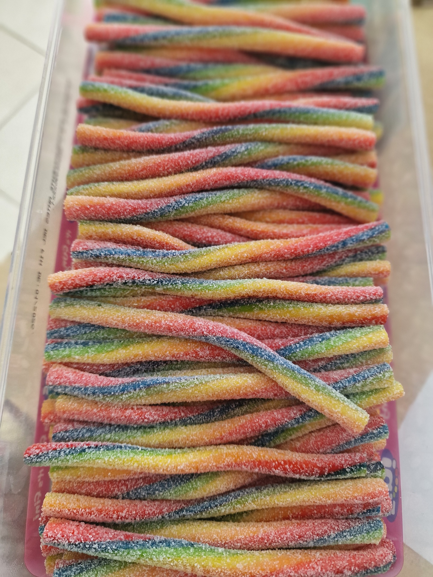 Tiras de bala de goma coloridas cobertas de açúcar numa embalagem transparente