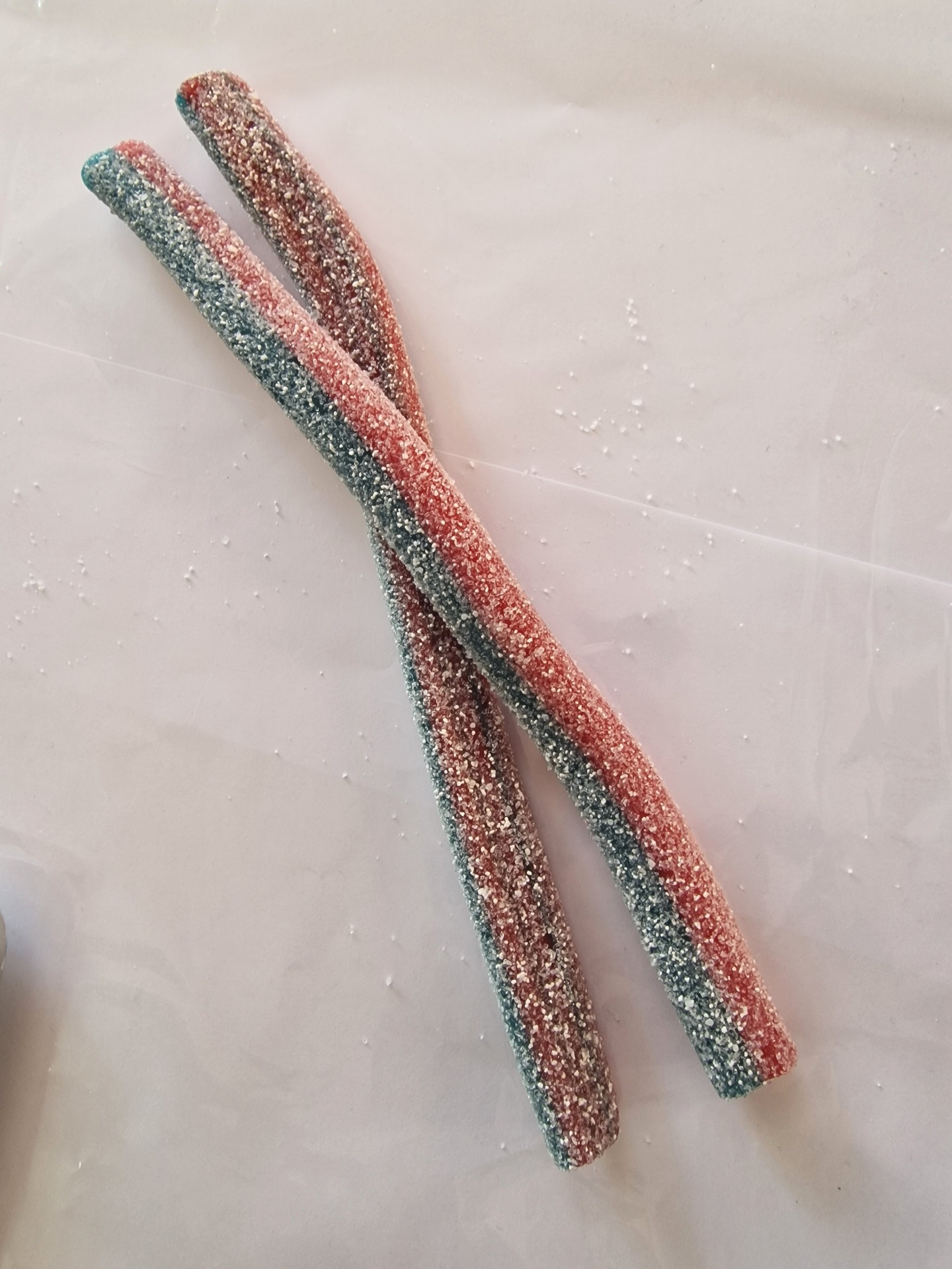 Dois doces compridos cobertos de açúcar com cores verde e vermelho.