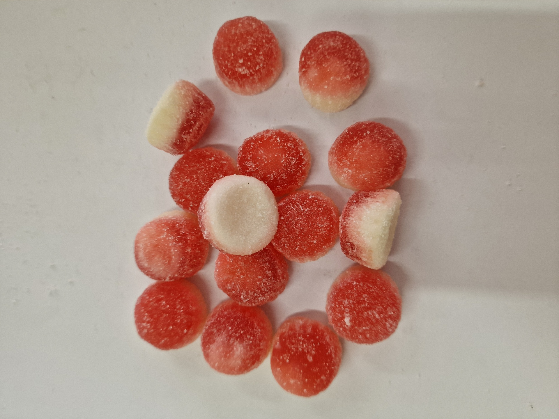 rebuçados redondos vermelhos e brancos cobertos de açúcar sobre fundo branco