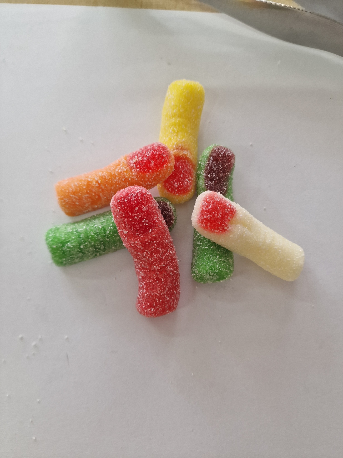 Gomas açucaradas coloridas em forma de vermes sobre superfície branca