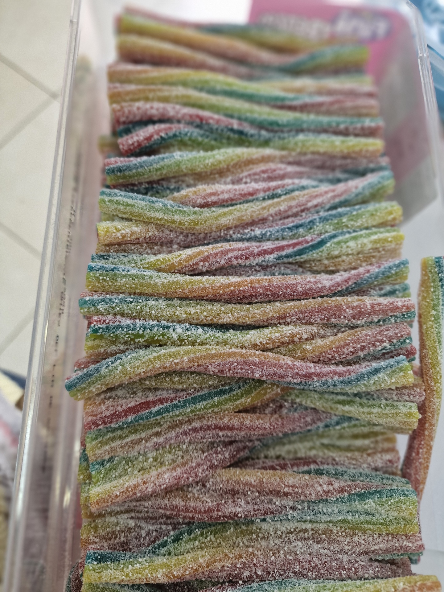 Doces coloridos em tiras cobertas de açúcar numa caixa transparente