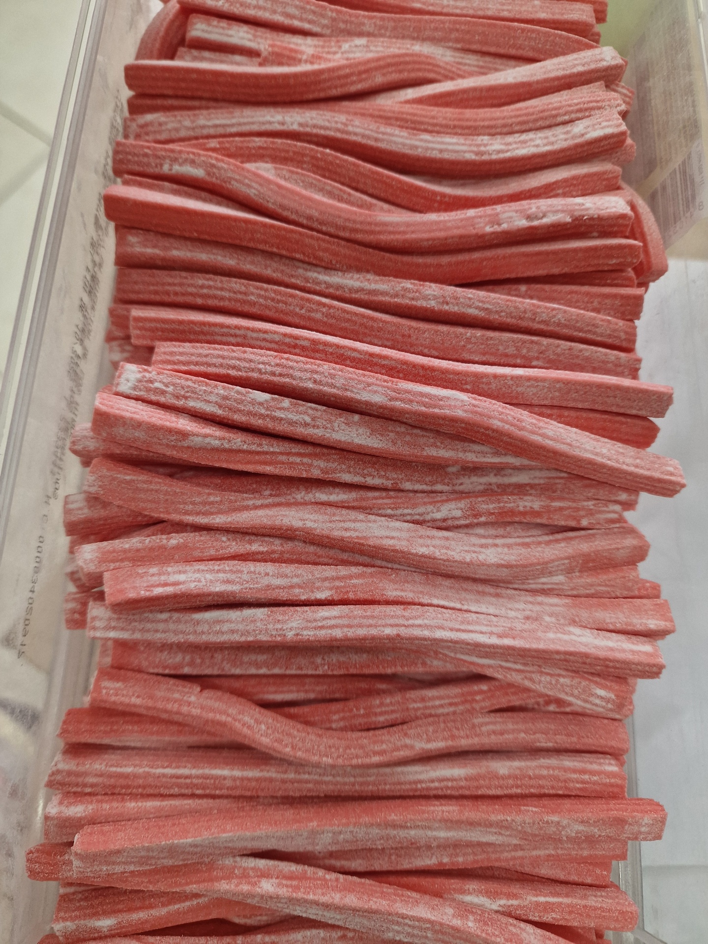 Bastões de doce rosa com pó branco em recipiente transparente