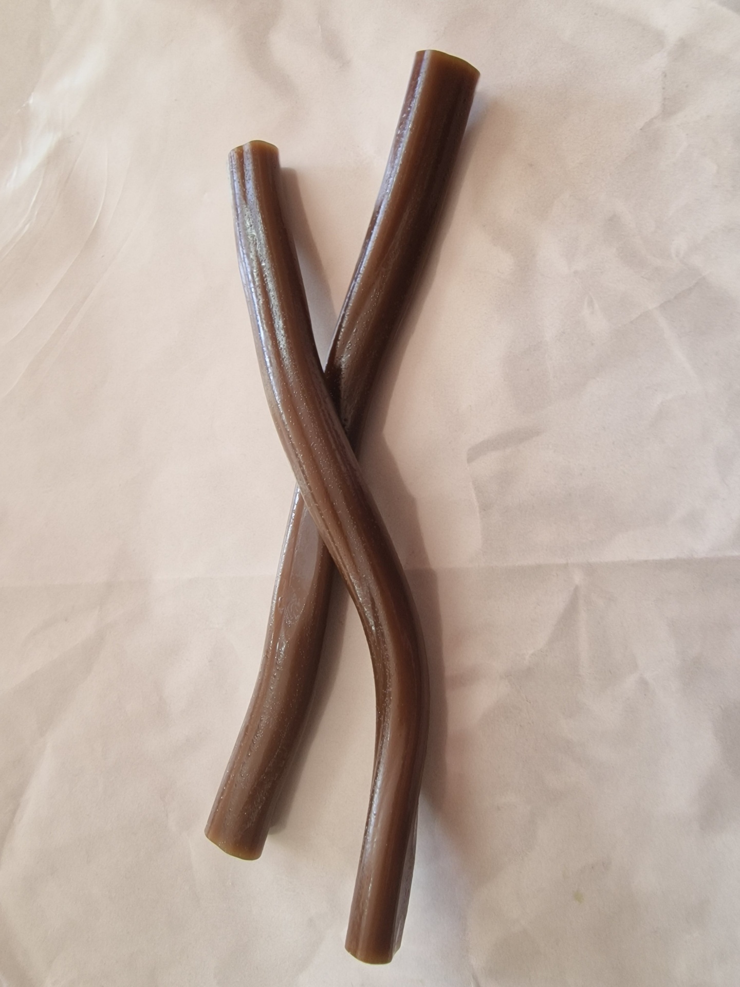 Dois tubos castanhos brilhantes cruzados sobre superfície branca
