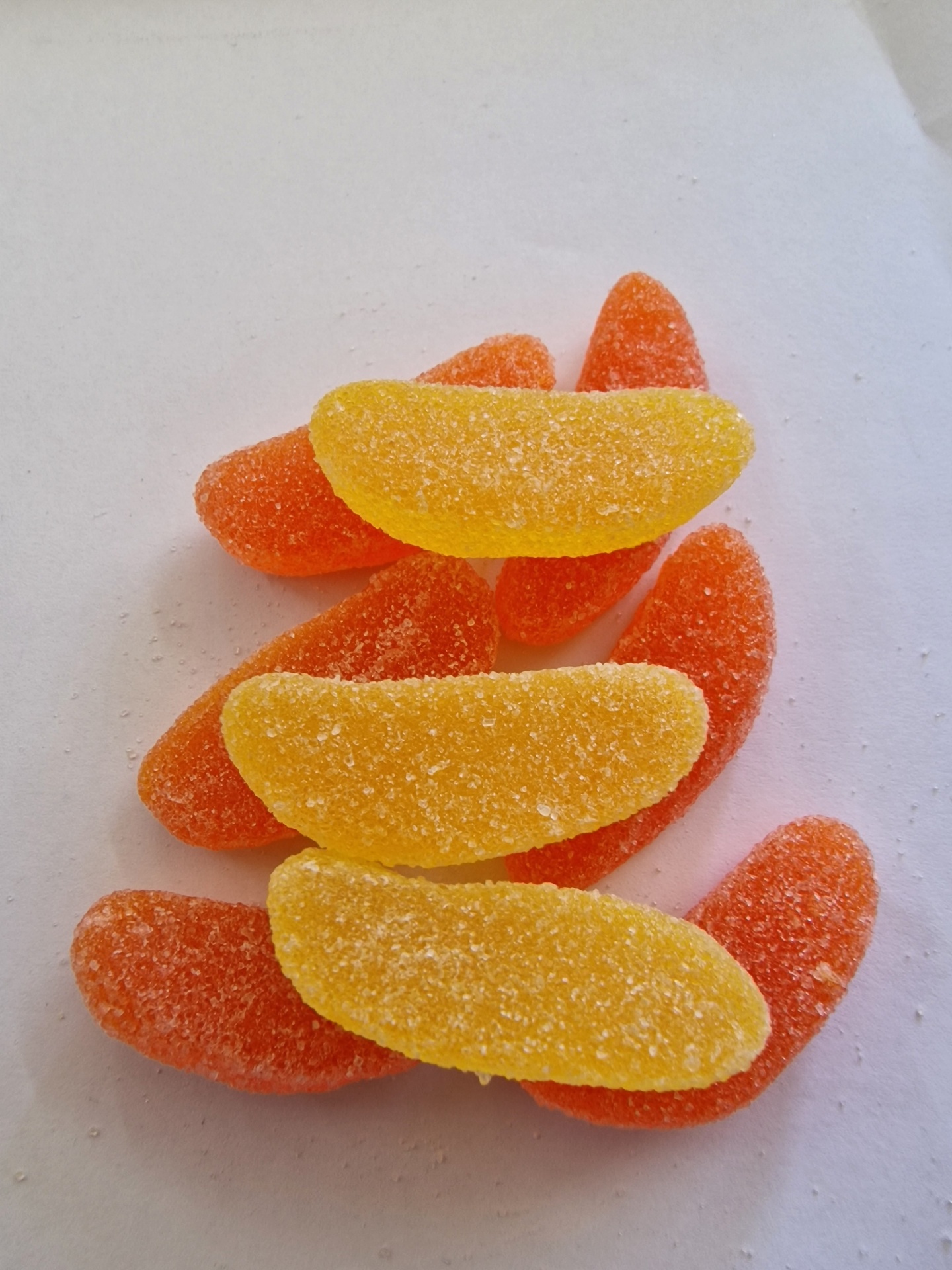 Gomas açucaradas em forma de gomos de fruta laranja e amarelo