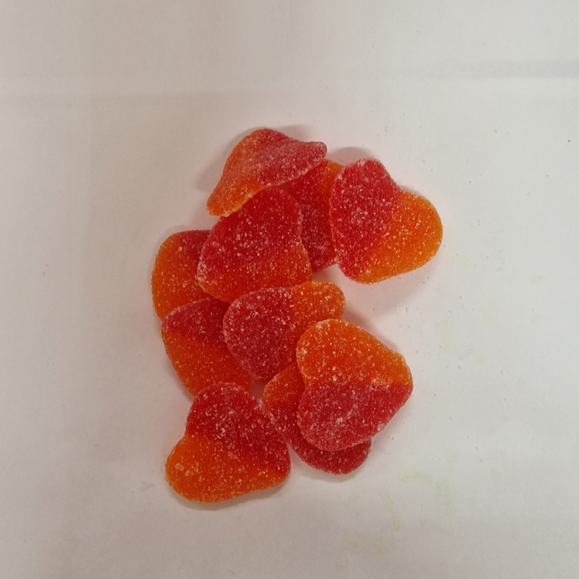 Doces em forma de coração vermelhos e laranja com açúcar sobre superfície branca