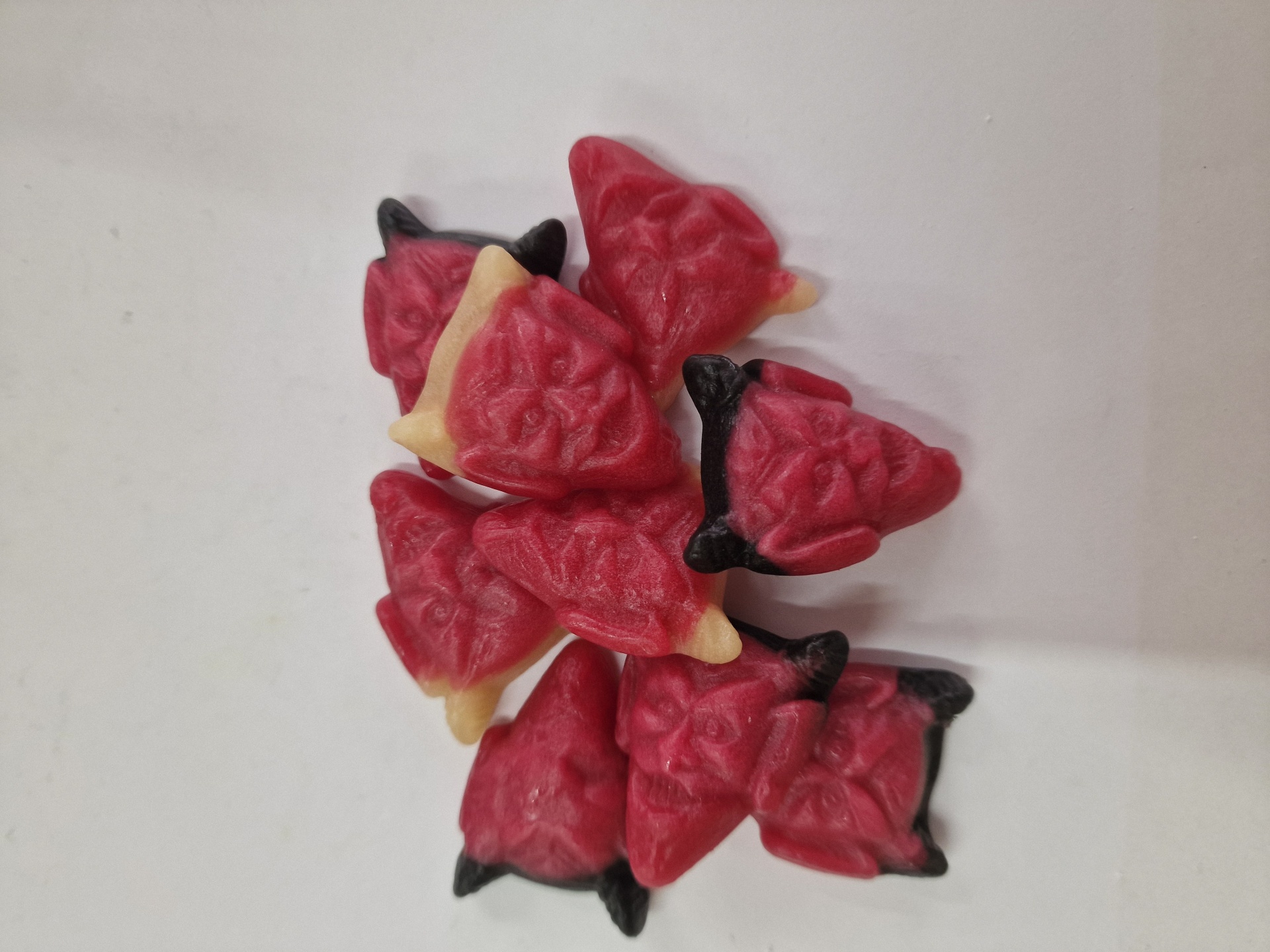 Gomas triangulares vermelhas com base amarela e pontas pretas sobre fundo branco