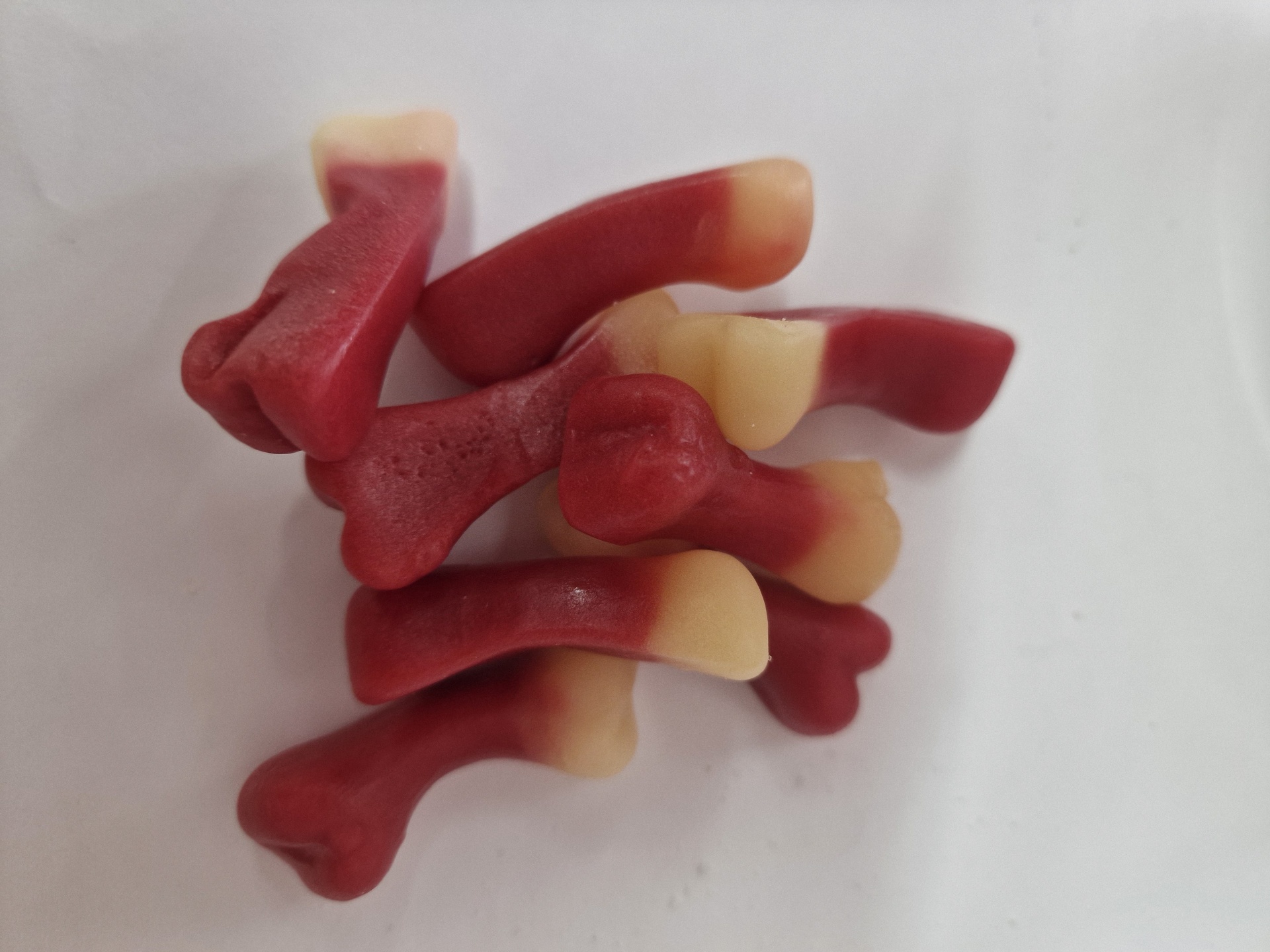 Gelatinosos em forma de ossos vermelhos e creme sobre fundo branco