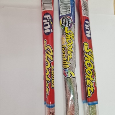 Três doces FINI Shooters em embalagens transparentes com etiquetas vermelhas e azuis.