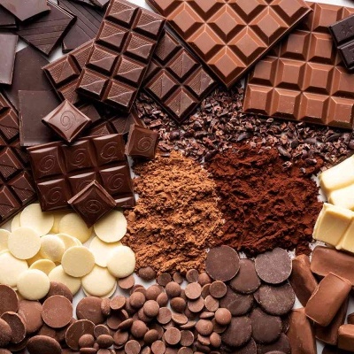 Diferentes tipos de chocolates em barras, gotas e ralados diversos em várias tonalidades de castanho e branco