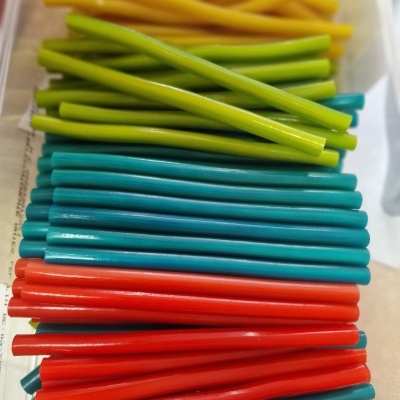 Tubos ou hastes coloridas em quatro cores alinhadas, sobre superfície clara