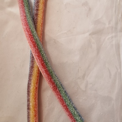 Dois bastões de doces coloridos com açúcar granulado sobre tecido claro