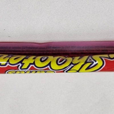 Doce comprido em embalagem plástica vermelha, azul e amarela com texto visível.