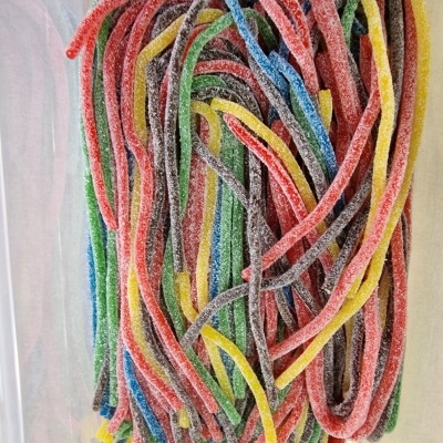 Doces em gelatina coloridos, compridos e açucarados em caixa de plástico